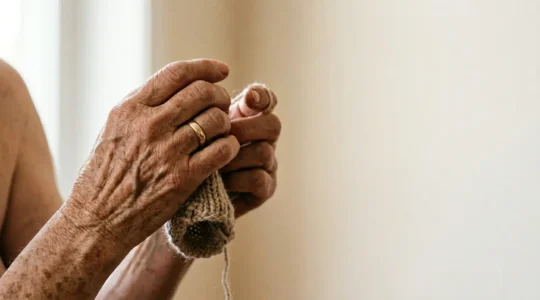 Close-up of senior hands gently moving in natural light, showing tactile warmth and careful motion, symbolizing the therapeutic value of movement over rest for arthritic joints