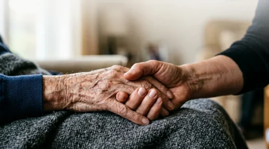 A caregiver's hands gently holding the weathered hands of an elderly person, symbolizing the emotional weight and compassion of family caregiving