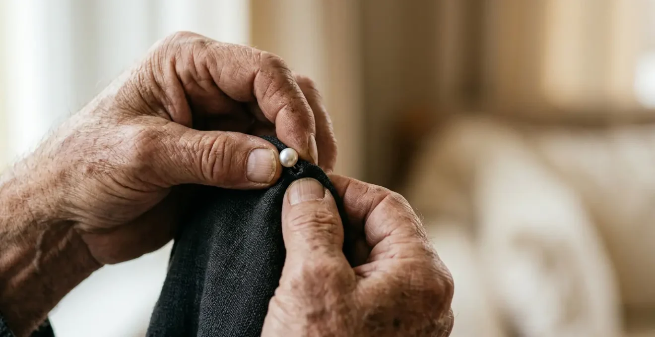 Close-up of elderly hands struggling with small clothing buttons, symbolizing daily living challenges