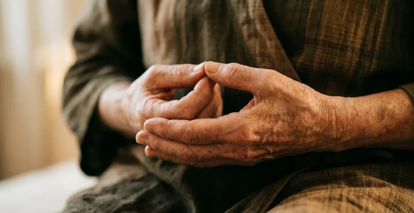 Macro detail of elderly hands positioned in mindful breathing gesture with soft morning sunlight