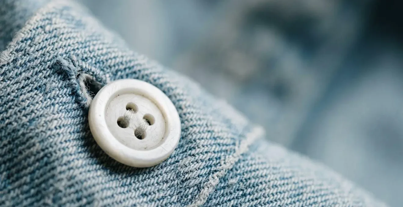 Macro close-up of a shirt button, highlighting the fine detail of the buttonhole and fabric weave